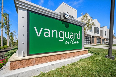 a sign for vanguard villas with a building in the background