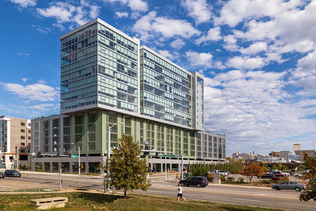 A large glass building with a green roof stands in front of a cloudy sky. at One Foundry Way Apartments, St Louis, MO, 63110