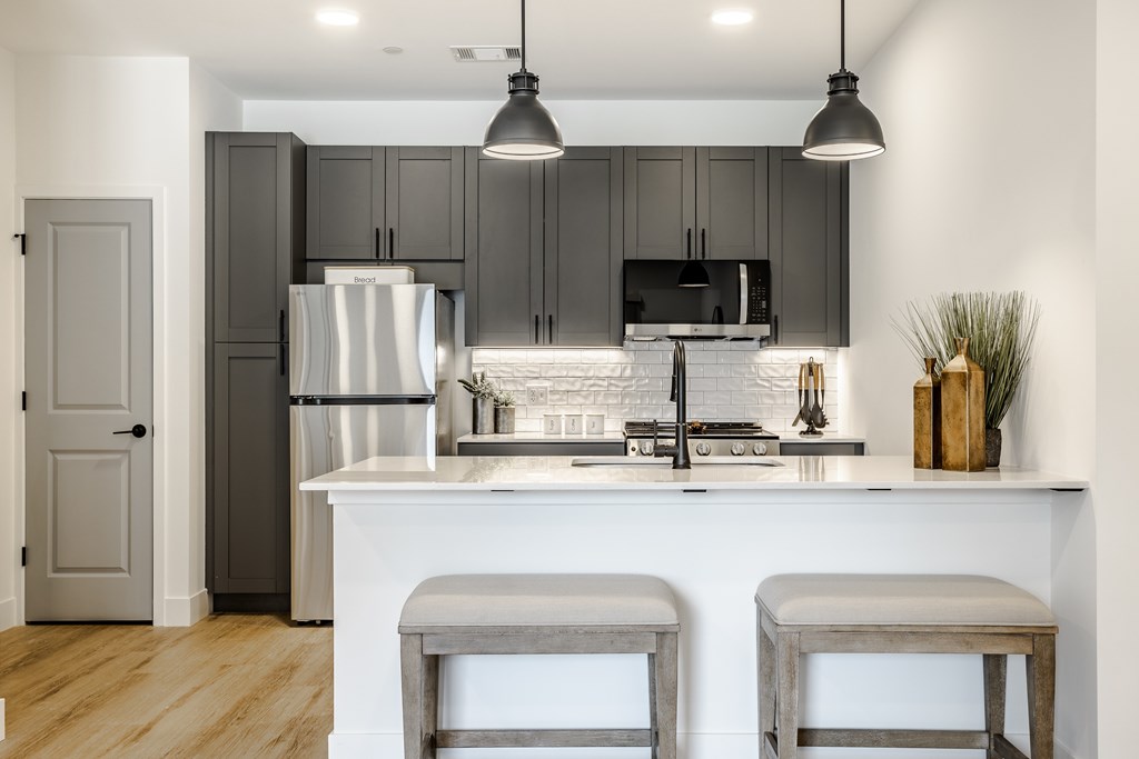 A modern kitchen with a white island and grey cabinets.