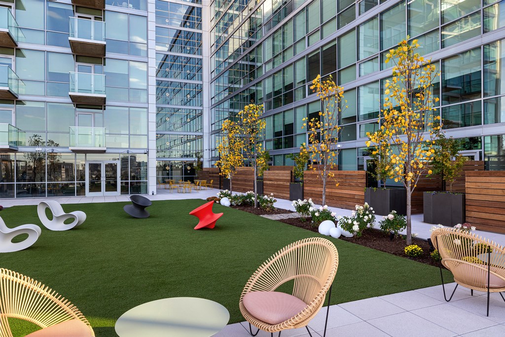 A modern outdoor seating area with wicker chairs and tables. at One Foundry Way Apartments, St Louis