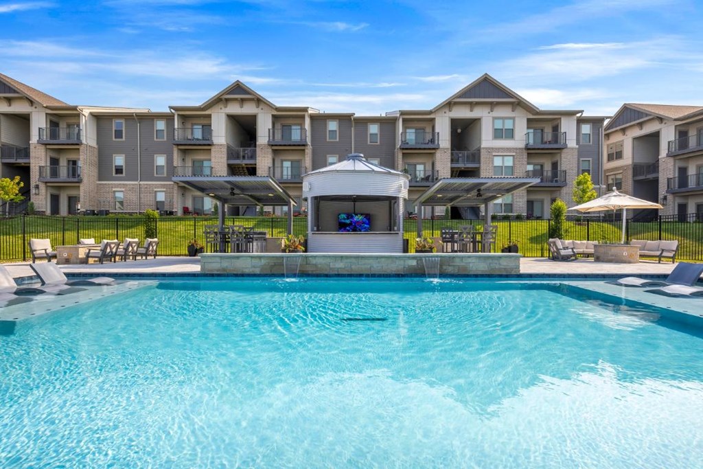 a swimming pool with an apartment building in the background at The Prairie Luxury Apartments, Dardenne Prairie Missouri