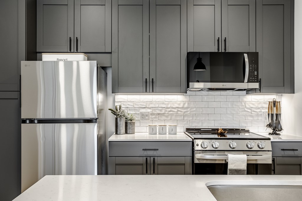 A modern kitchen with a refrigerator, stove, and microwave.