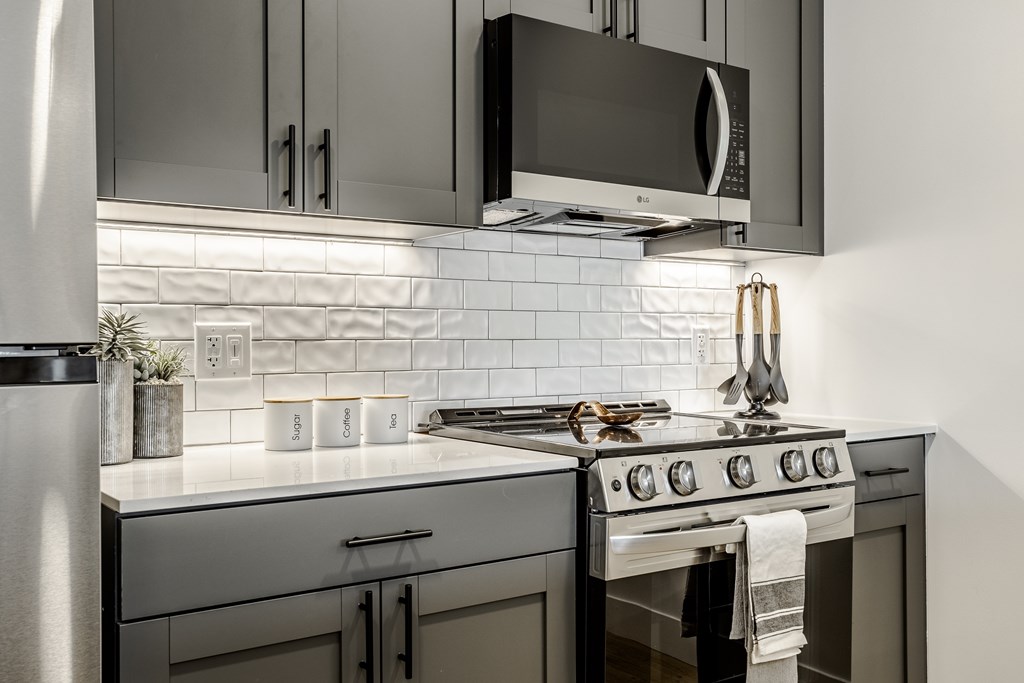 A modern kitchen with a stove, microwave, and oven.