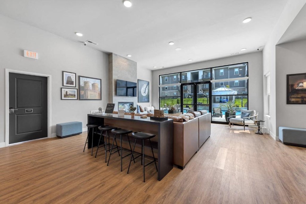 a kitchen and living room with a bar and a large window at The Prairie Luxury Apartments, Dardenne Prairie, MO