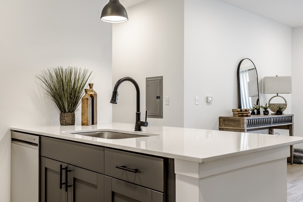 A modern kitchen with a white countertop and black faucet.