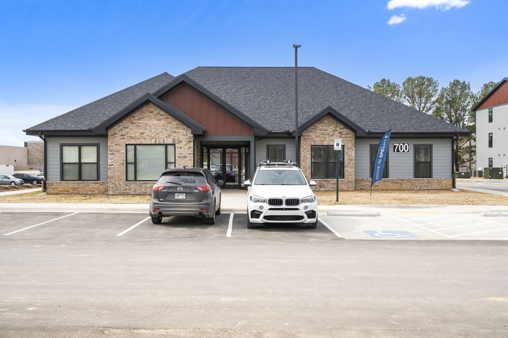 a parking lot with two cars in front of a building at The Junction at Rogers, Rogers, 72756