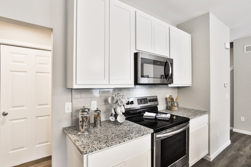 a kitchen with white cabinets and a black stove and microwave at The Willows, O'Fallon, 63367