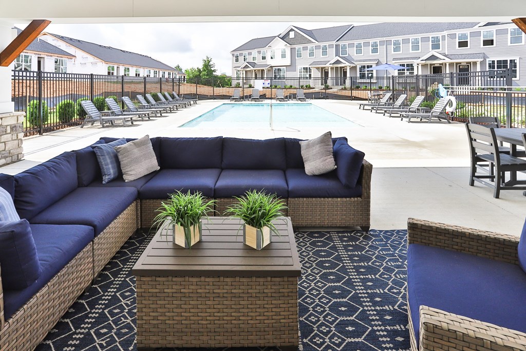 the outdoor lounge area of a resort pool with blue couches and tables
