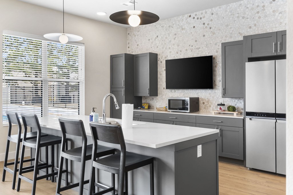 a kitchen with gray cabinets and a white island with chairs at The Junction at Rogers, Rogers, Arkansas