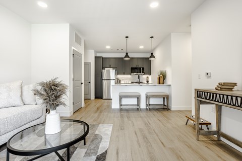 A modern living room with a glass table and a grey sofa.