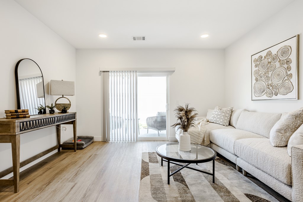 A living room with a white couch, a coffee table, and a large mirror.