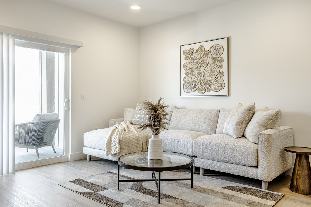 A living room with a white couch, a coffee table, and a large window.