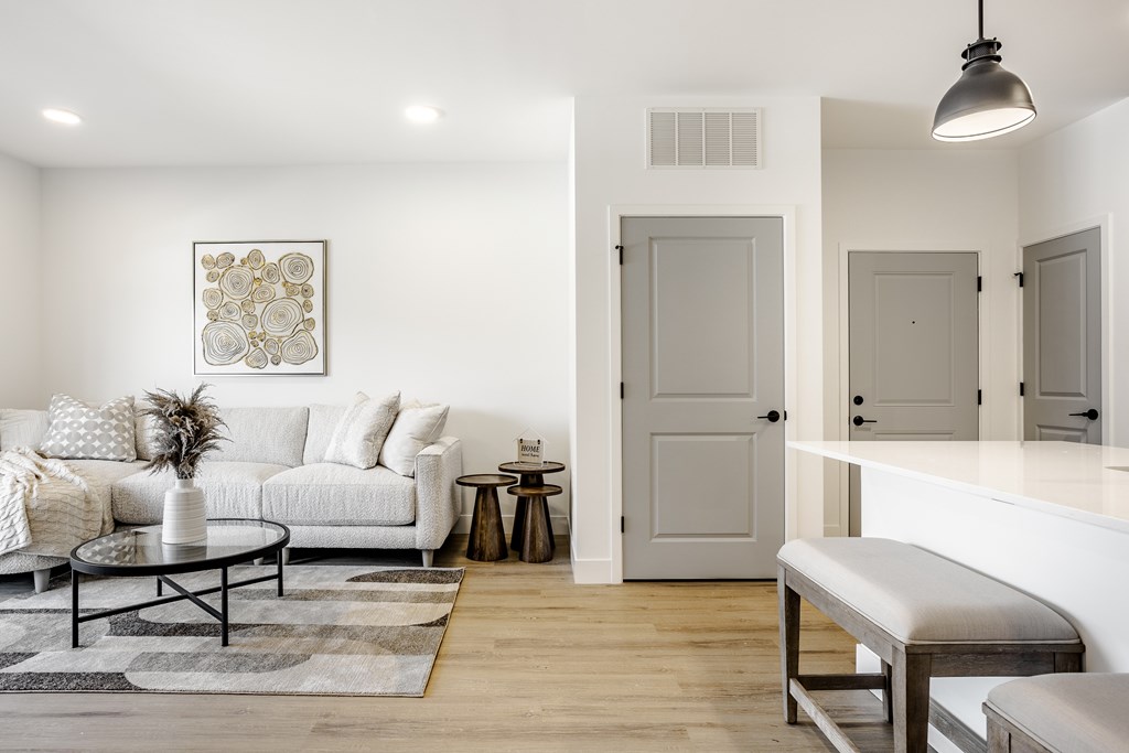 A white living room with a couch, coffee table, and a painting on the wall.