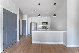 an open kitchen and living room with a white counter top and a blue door