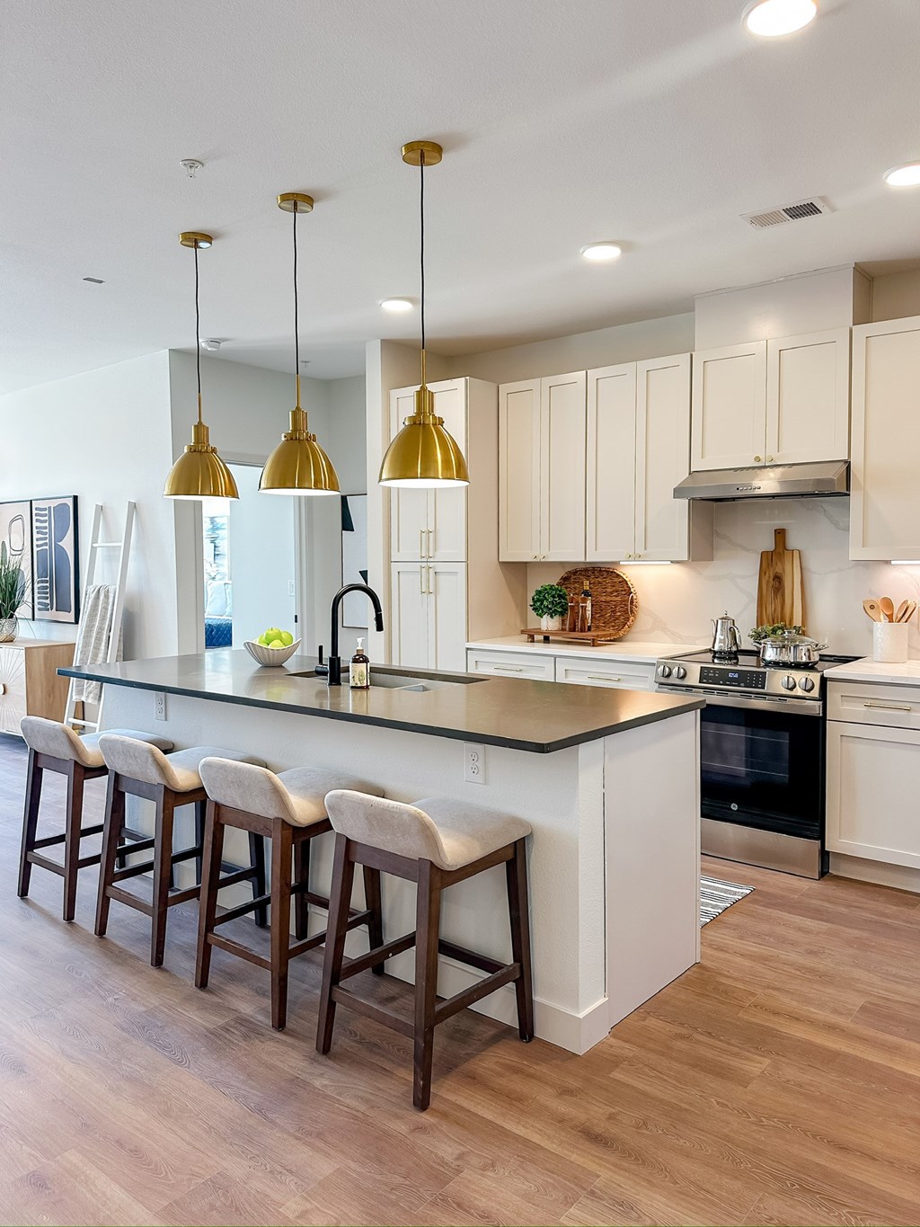 A kitchen with white cabinets and a bar area with stools.