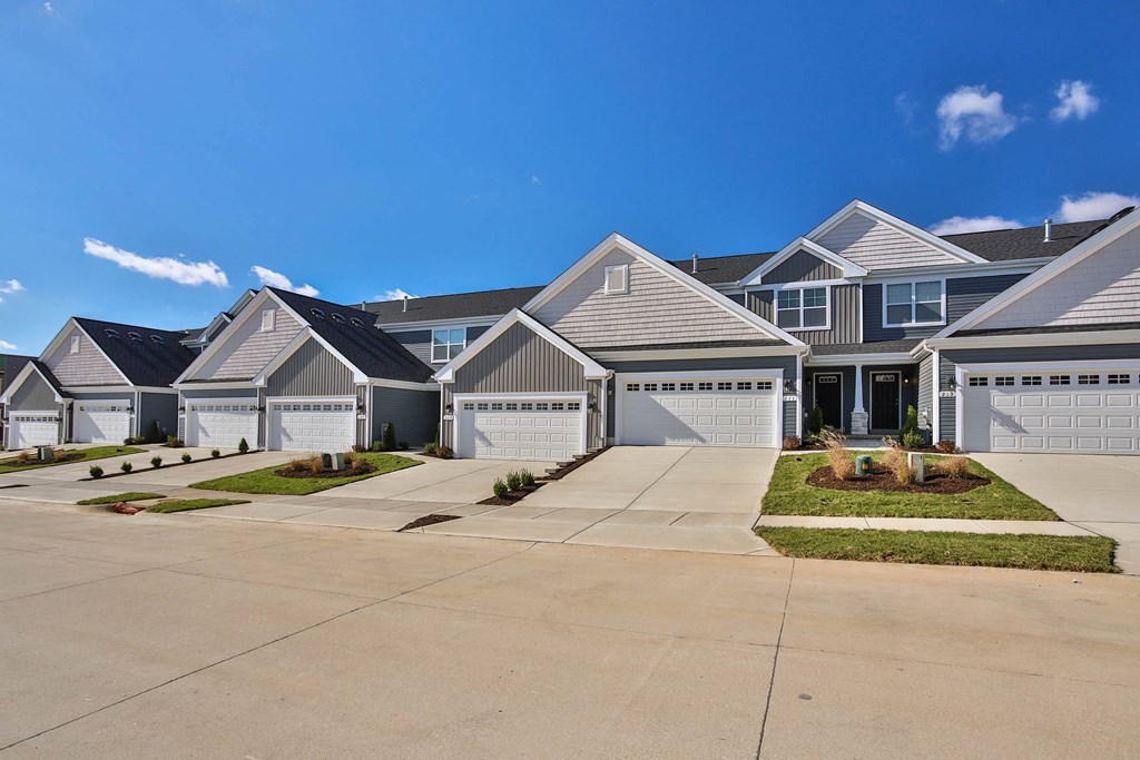 a row of houses in a neighborhood with a blue sky at The Prairie Villas, Dardenne Prairie, 63368