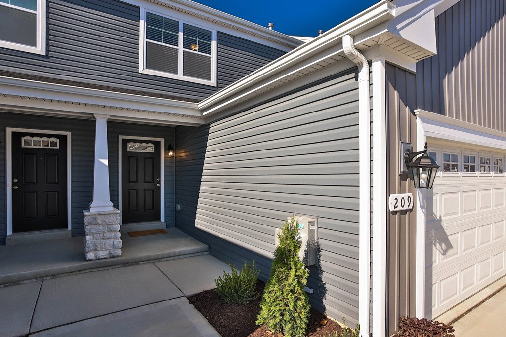 the front of a blue house with a driveway and a garage door at The Prairie Villas, Dardenne Prairie, MO
