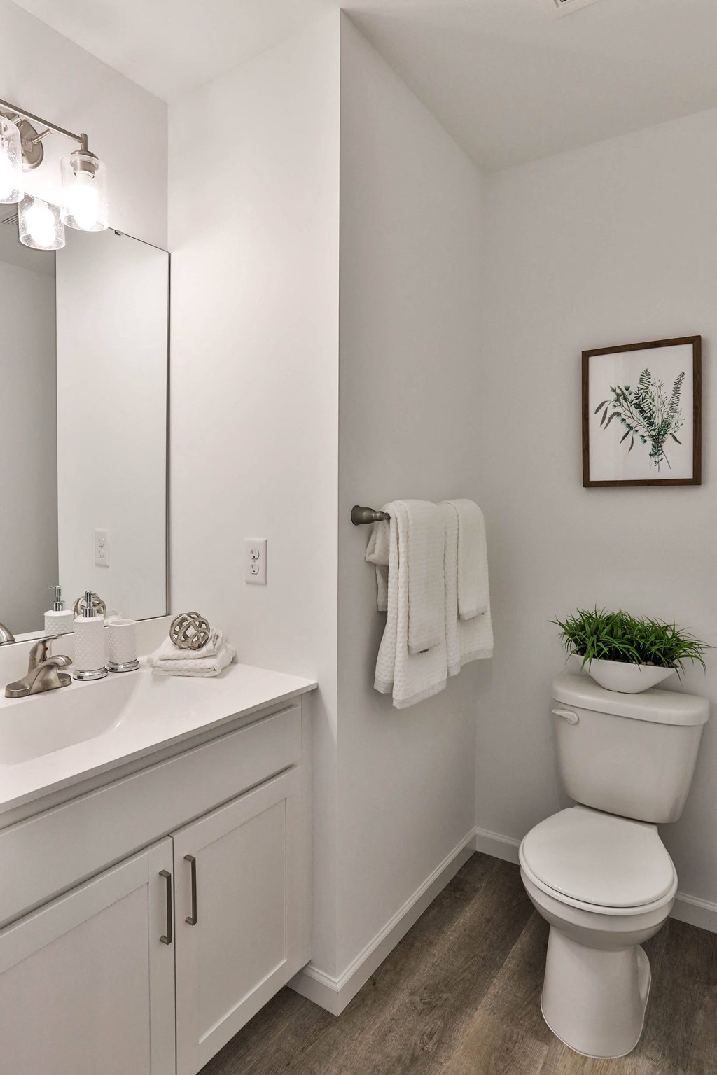a bathroom with a toilet and a sink and a mirror at The Prairie Villas, Dardenne Prairie, Missouri