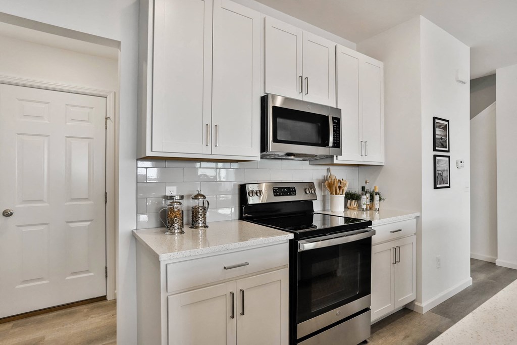 a kitchen with white cabinets and a stove and a microwave at The Prairie Villas, Missouri, 63368
