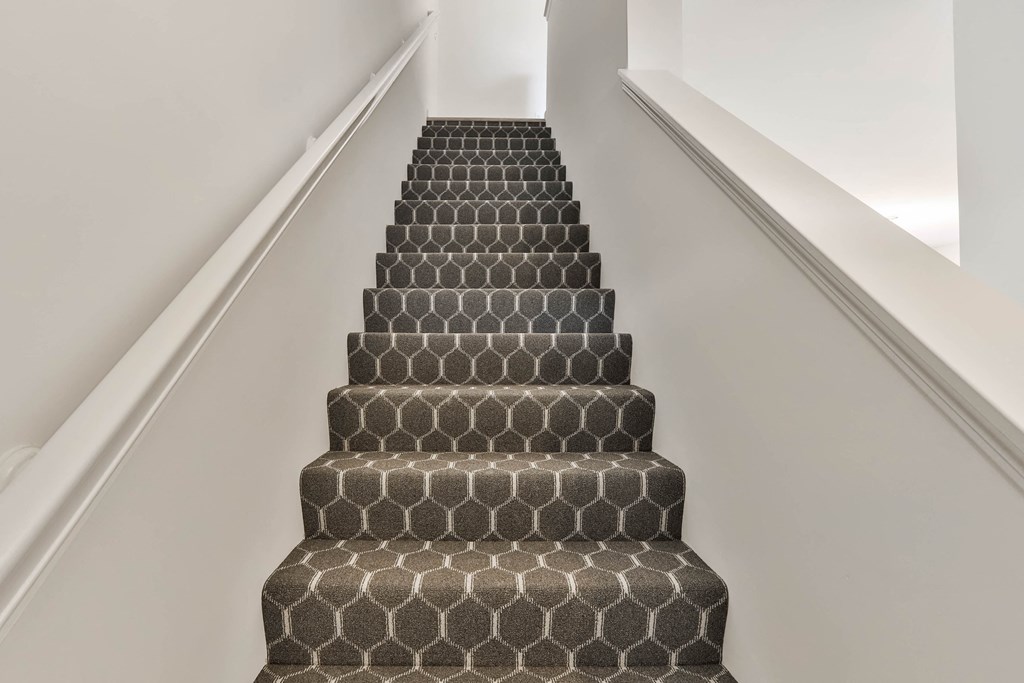 a flight of stairs with a black and white carpeted stair case and white walls at The Prairie Villas, Missouri, 63368