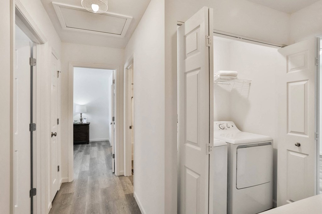 a washer and dryer in a white laundry room with white walls and wood at The Prairie Villas, Dardenne Prairie