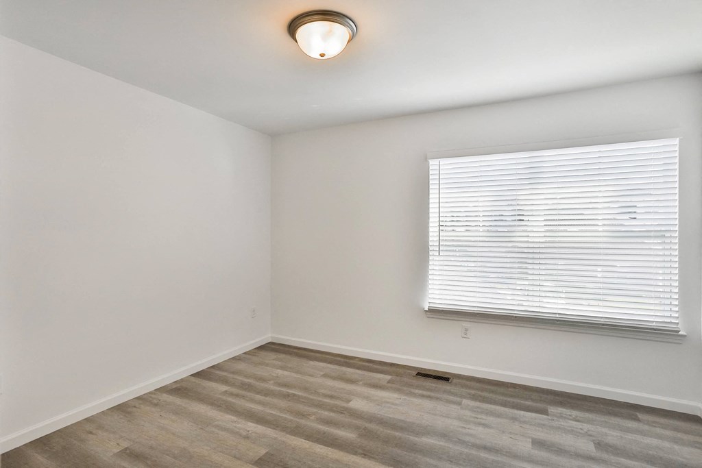 the living room of an apartment with a window and wood flooring at The Prairie Villas, Dardenne Prairie Missouri