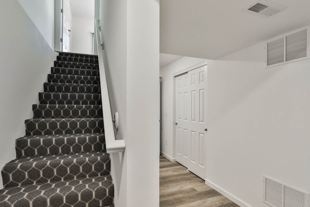 a staircase in a home with black and white stairs and a white door at The Prairie Villas, Dardenne Prairie, 63368