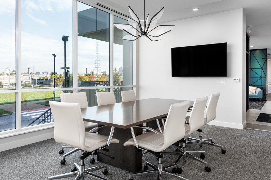 a conference room with a large window and a table with white chairs at 2200 LaSalle Apartments, St Louis, 63104
