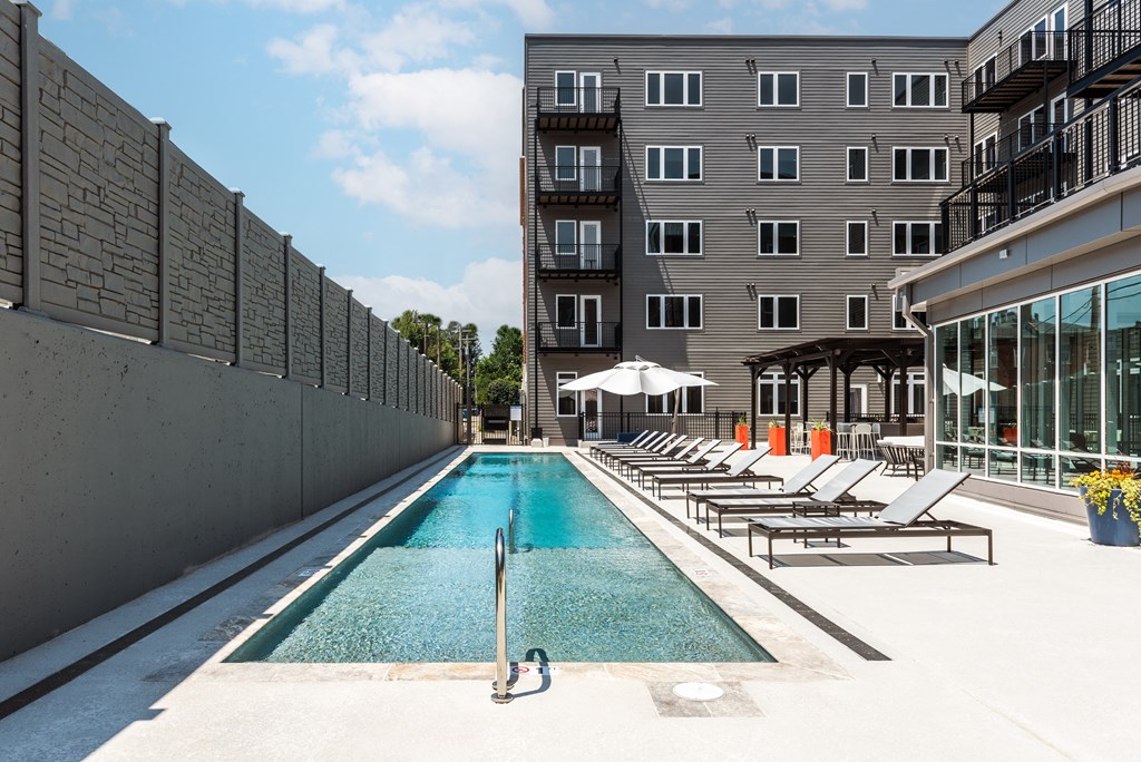 a swimming pool with lounge chairs next to a building at 2200 LaSalle Apartments, Missouri, 63104