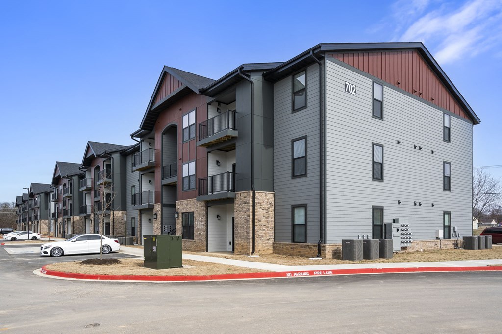 an apartment building with a car parked in front of it at The Junction at Rogers, Rogers, 72756