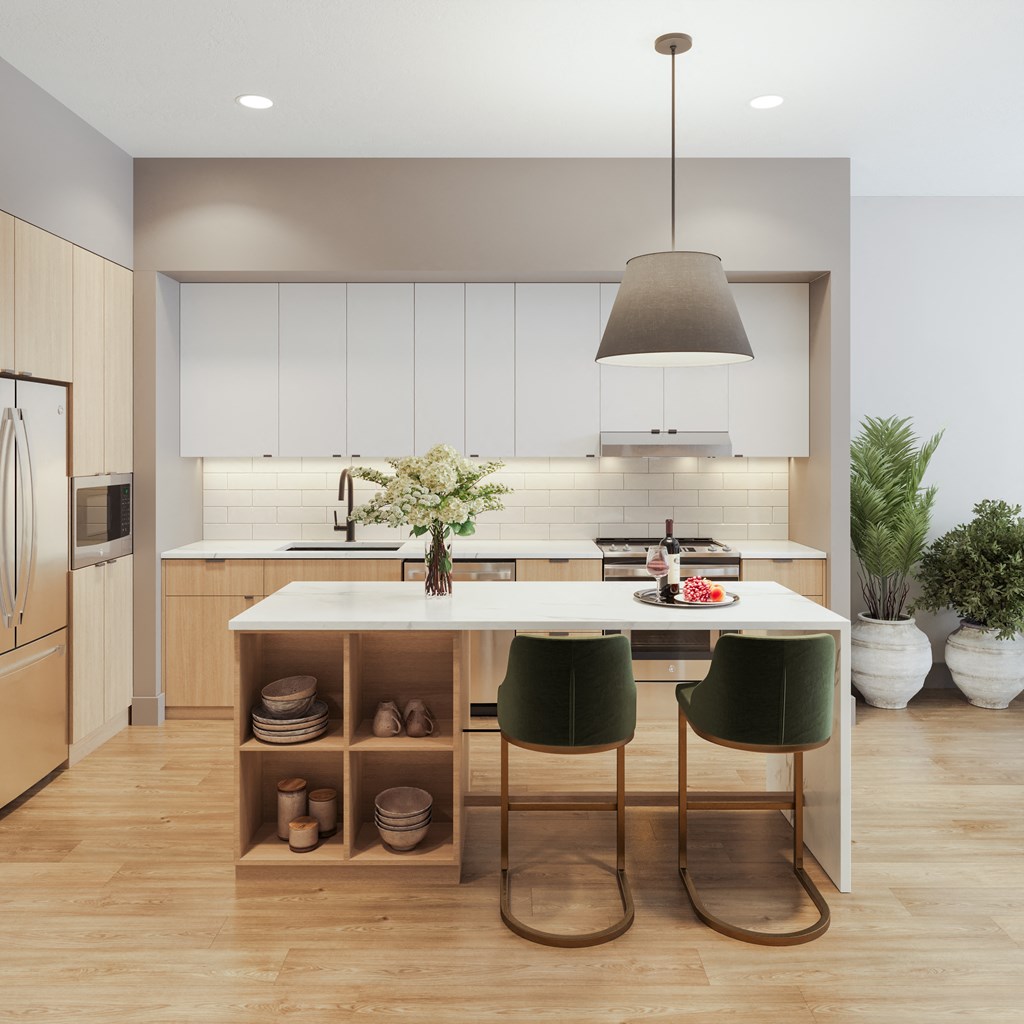 a kitchen with white cabinets and a white island with green chairs at Bemiston Place Apartments, Missouri, 63105