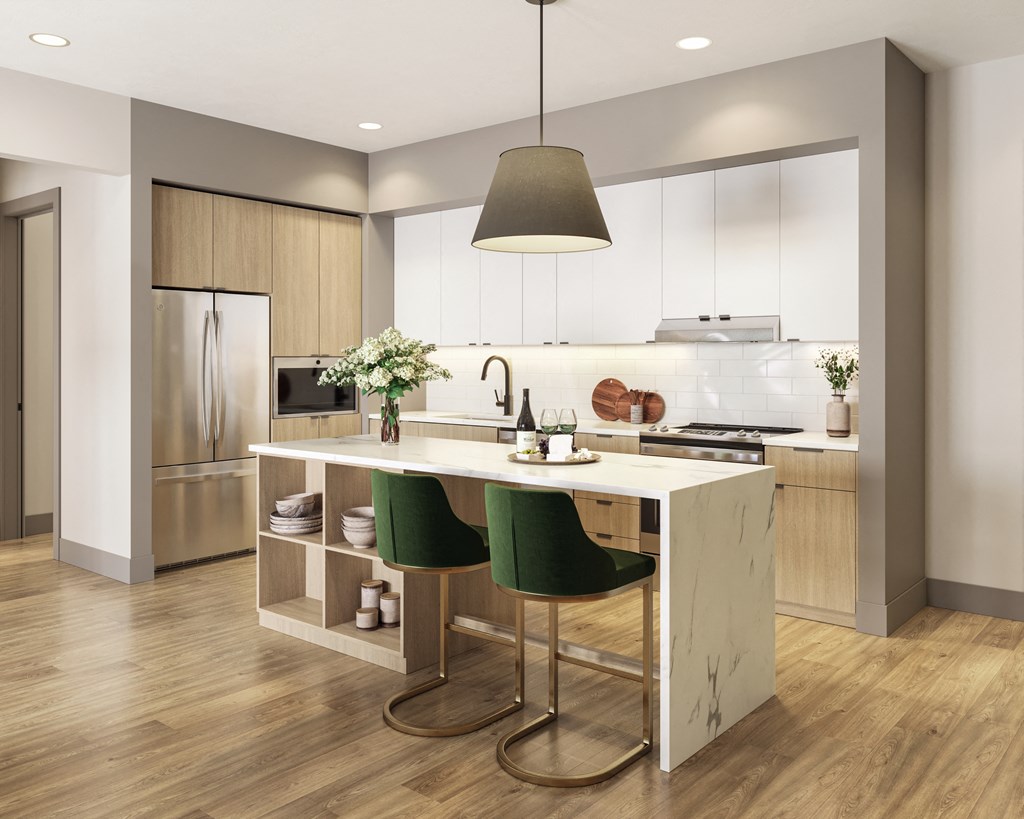 a kitchen with white cabinets and a white island with green chairs at Bemiston Place Apartments, Clayton