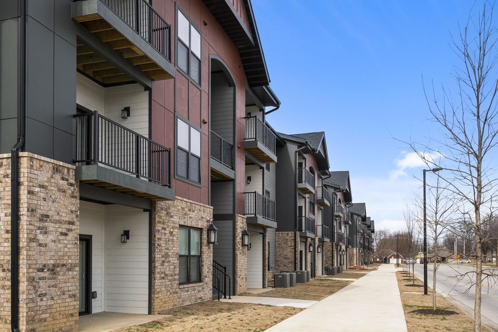 a row of town houses with balconies and a sidewalk at The Junction at Rogers, Rogers, Arkansas