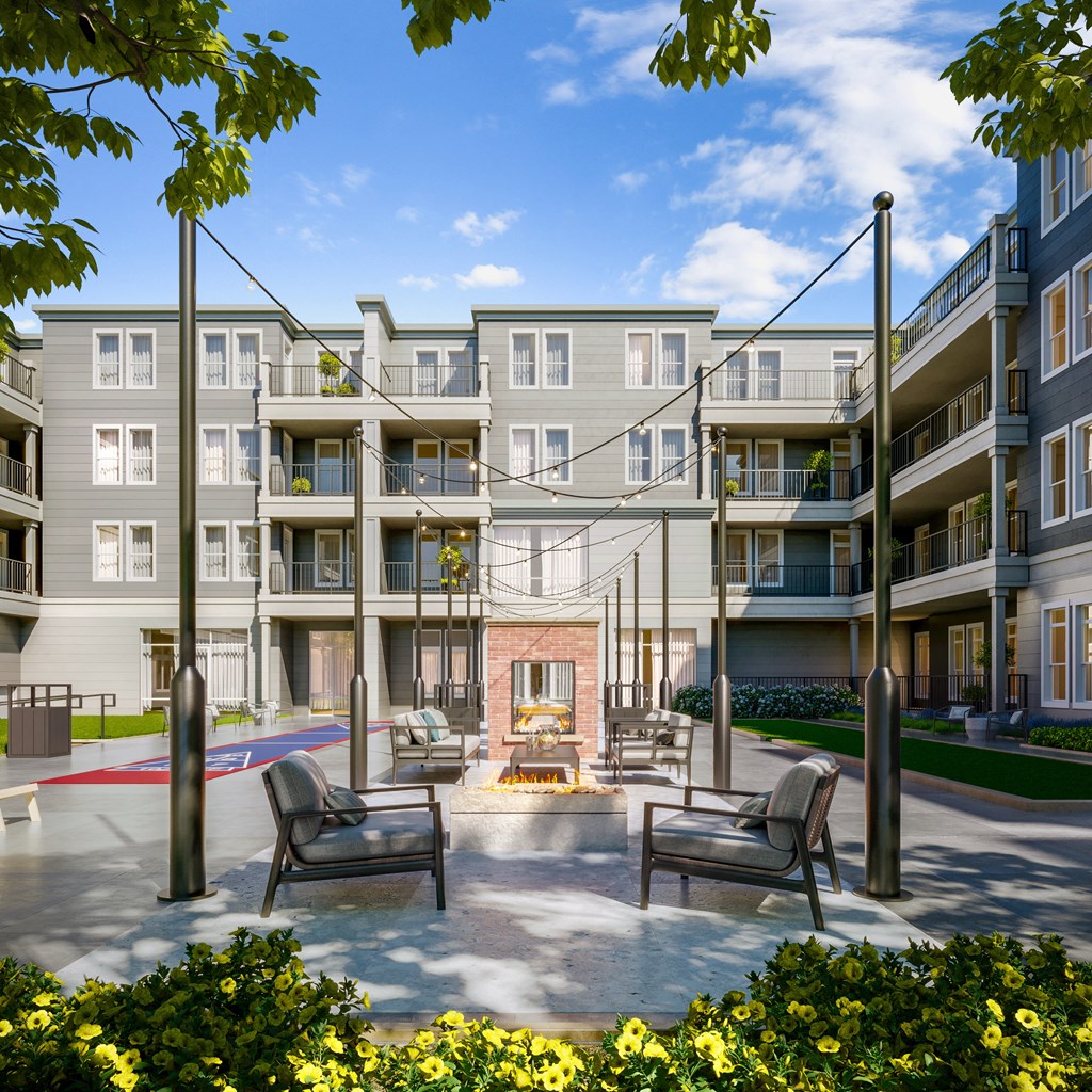 a courtyard with a fire pit and chairs in front of an apartment building