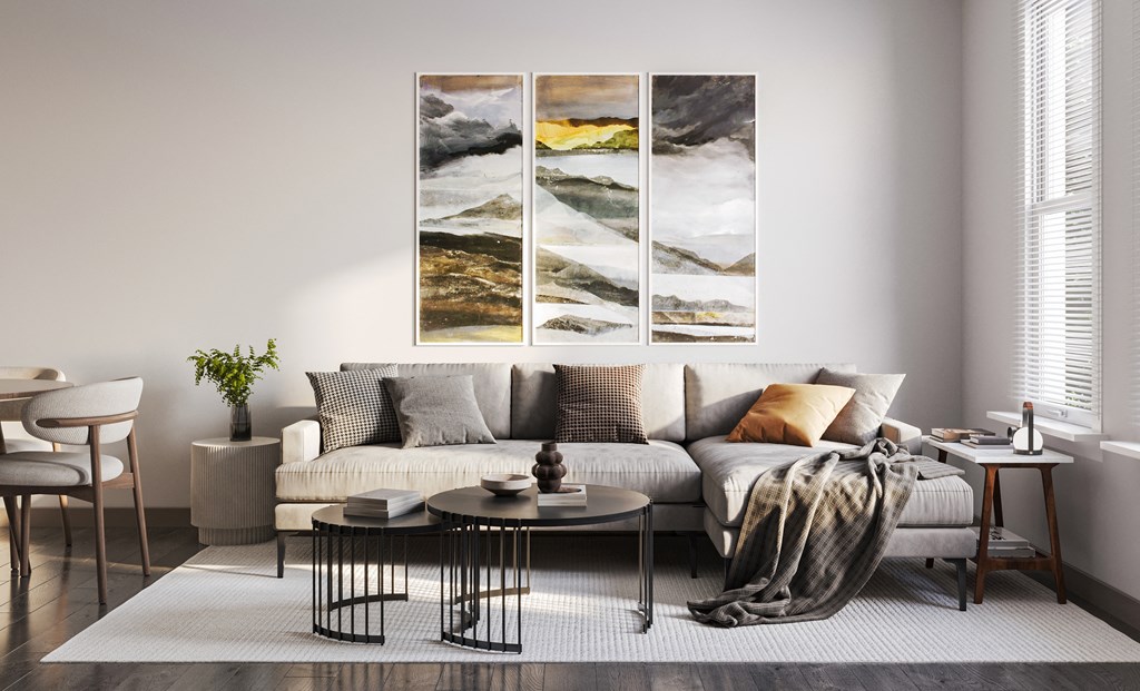 a living room with a couch and three paintings on the wall