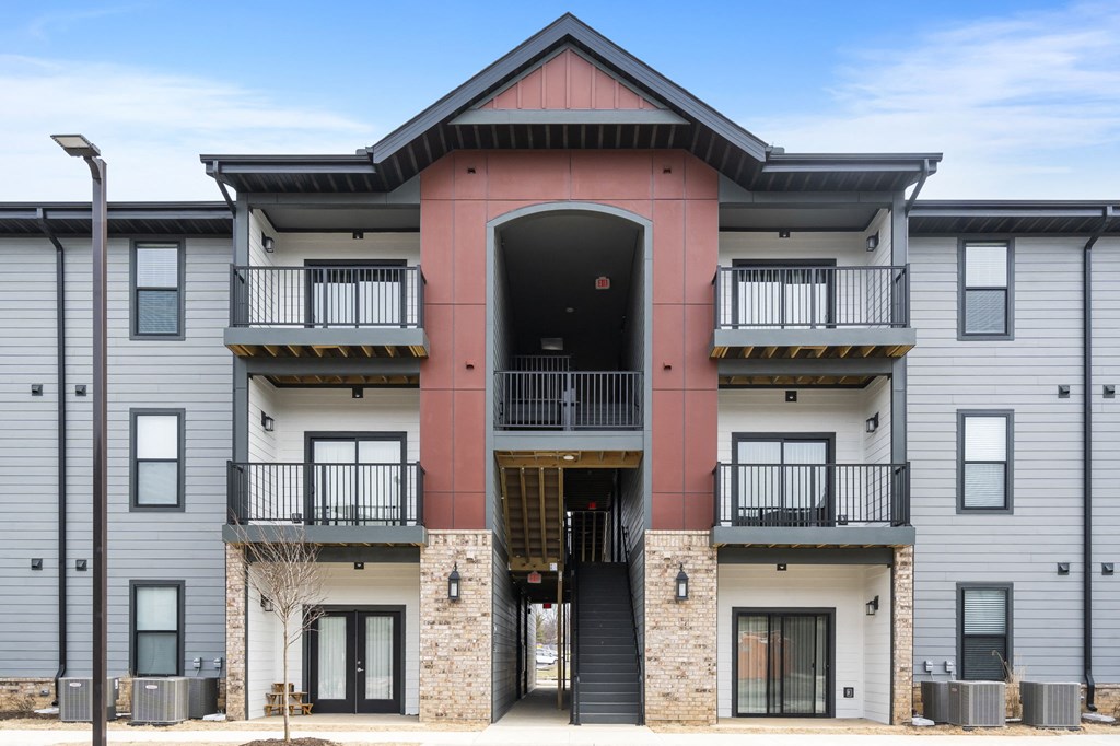 the exterior of a condo building with balconies and a pink and gray facade at The Junction at Rogers, Rogers