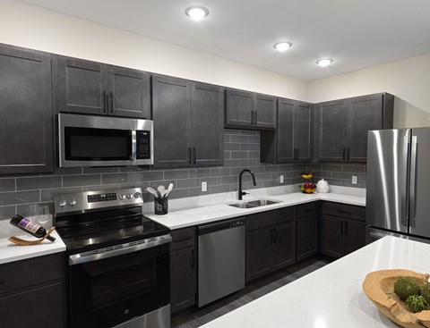 A modern kitchen with black cabinets and stainless steel appliances.