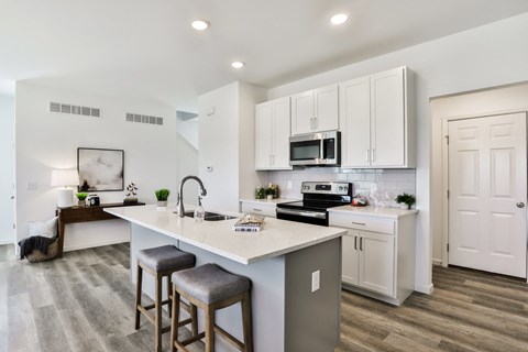 a kitchen with white cabinets and a large island with three stools