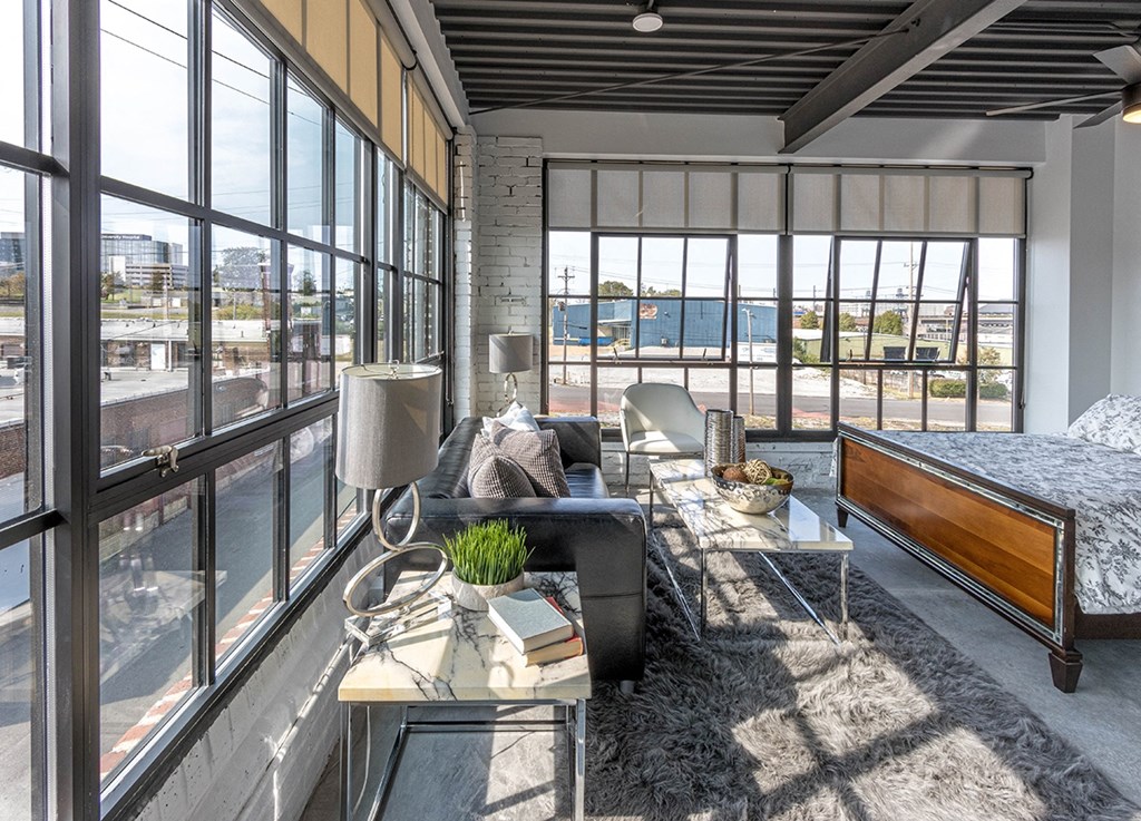 a living room with a couch and a table in front of large windows