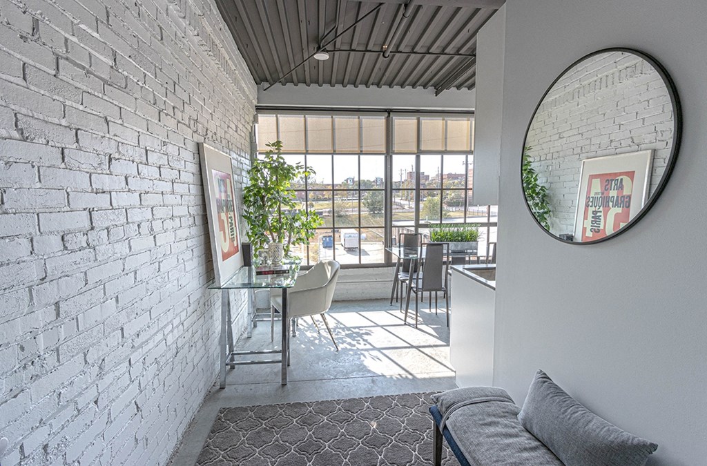 a round mirror hangs on a white brick wall in a living room with a table