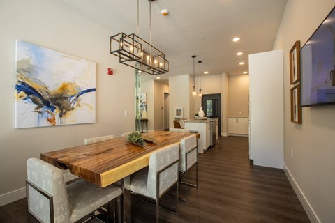 A modern dining room with a wooden table and chairs at The Elle on Lockwood Apartments, Webster Groves, Missouri