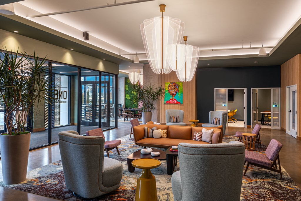 A modern living room with a grey sofa, a yellow coffee table, and a large chandelier.