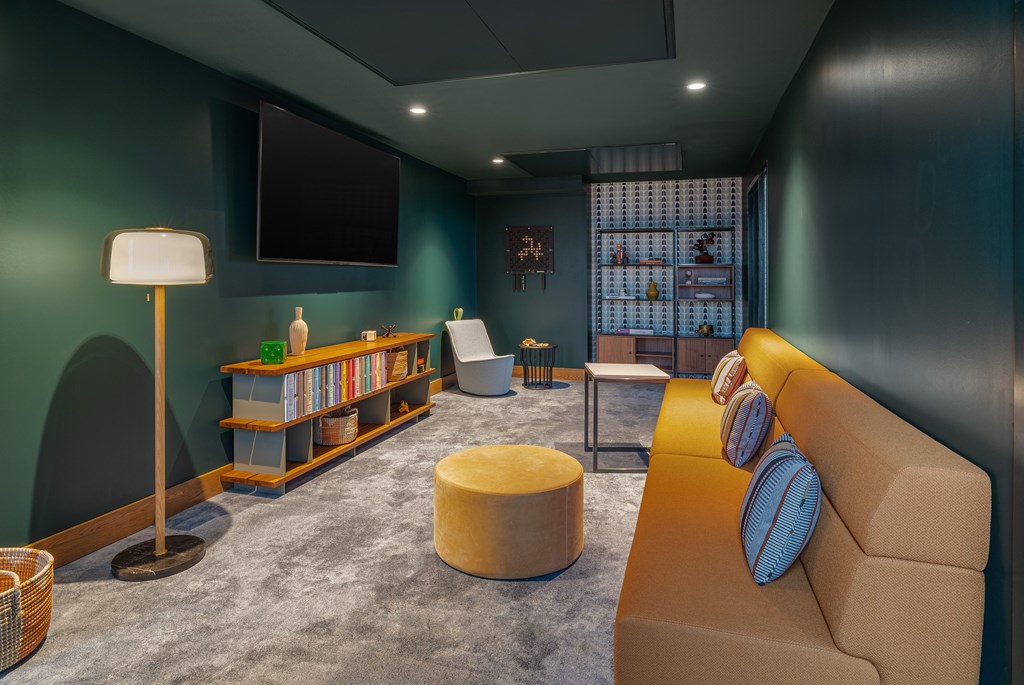 A living room with a couch, a chair, a floor lamp, a table, a TV, and a bookshelf.