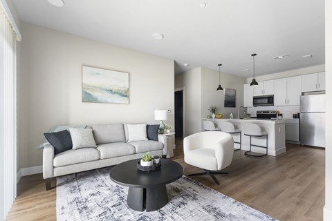 A modern living room with a grey sofa, a black coffee table, and a painting on the wall.