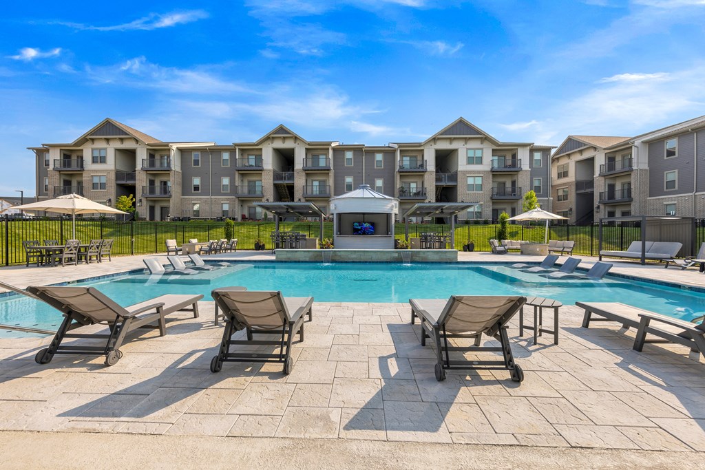 spacious pool deck with lounge chairs and sparkling pool with The Prairie Luxury Apartments in the background at The Prairie Villas, Missouri, 63368