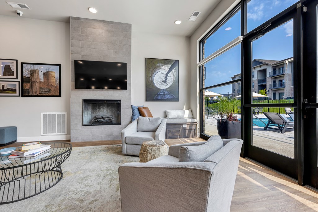 modern clubroom with floor to ceiling windows, fireplace, large tv and conversational seating at The Prairie Villas, Dardenne Prairie, MO