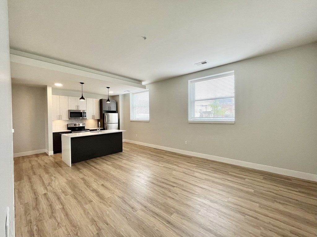 A spacious room with light wood flooring and a black and white counter.