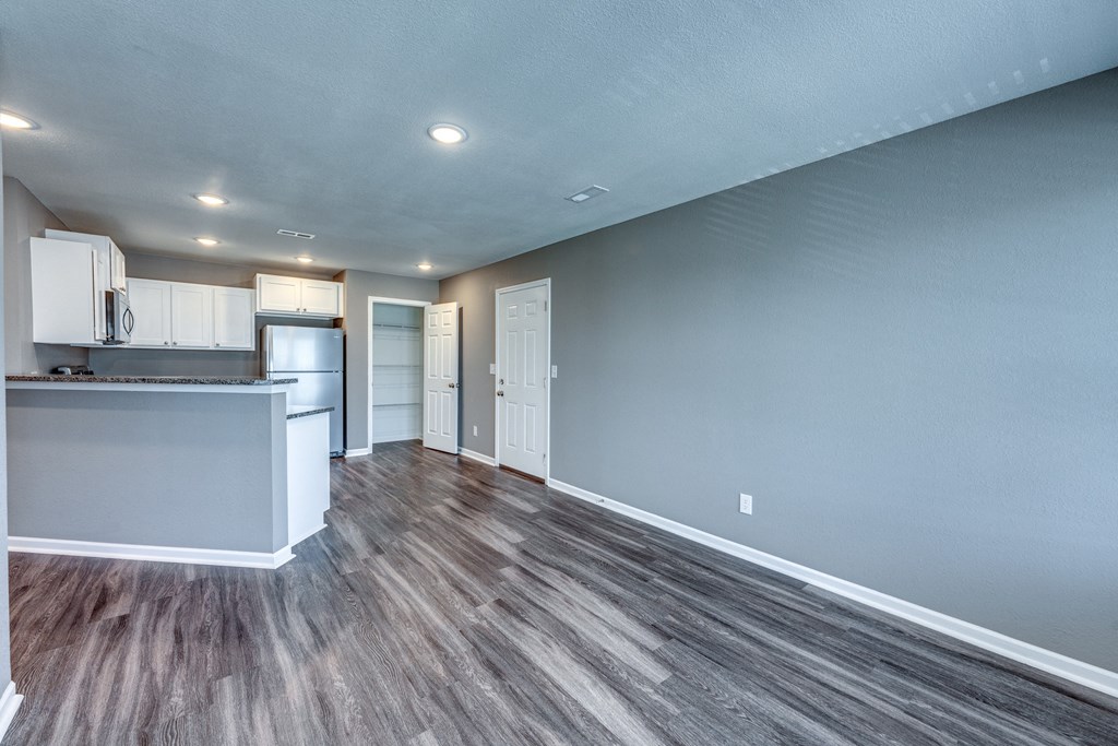 A kitchen with a white counter and cabinets with a grey wall.