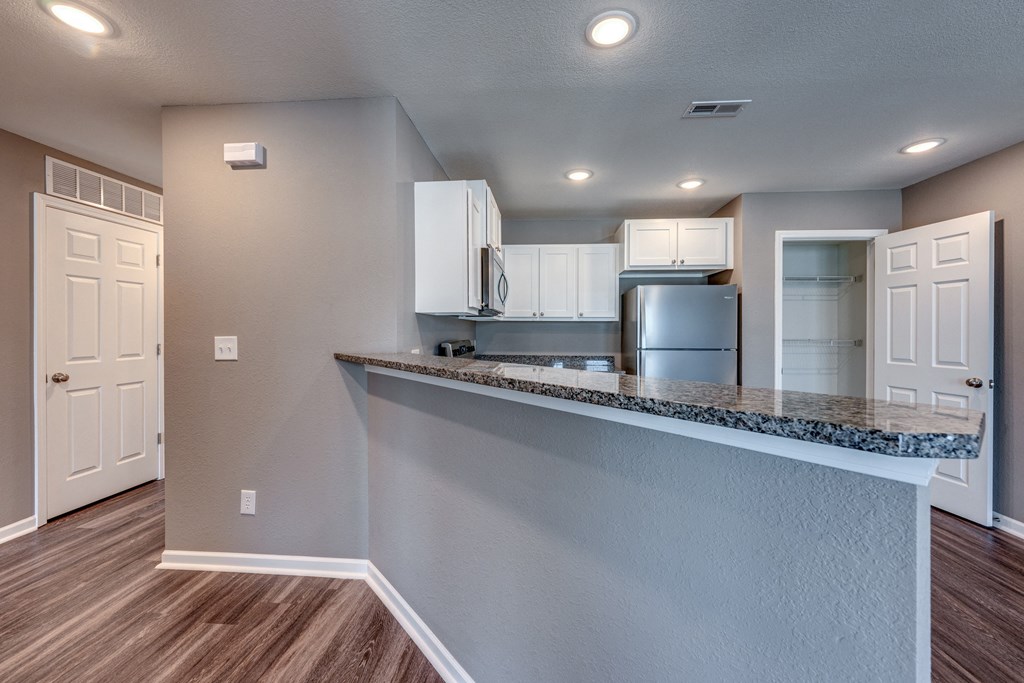A kitchen with white cabinets and a granite countertop.