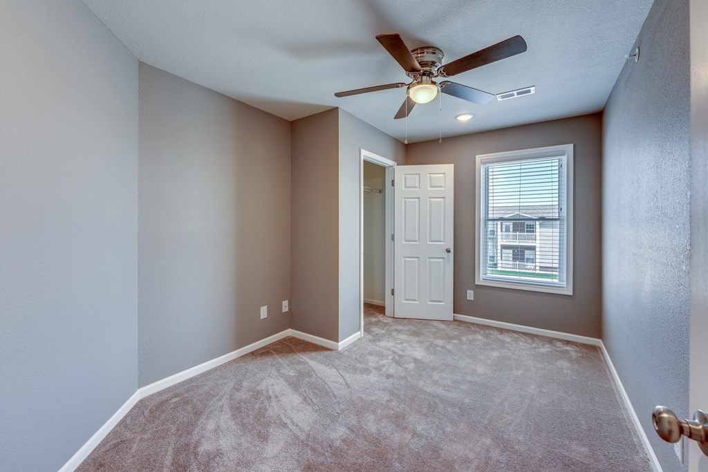 A room with a ceiling fan and carpeted floor.